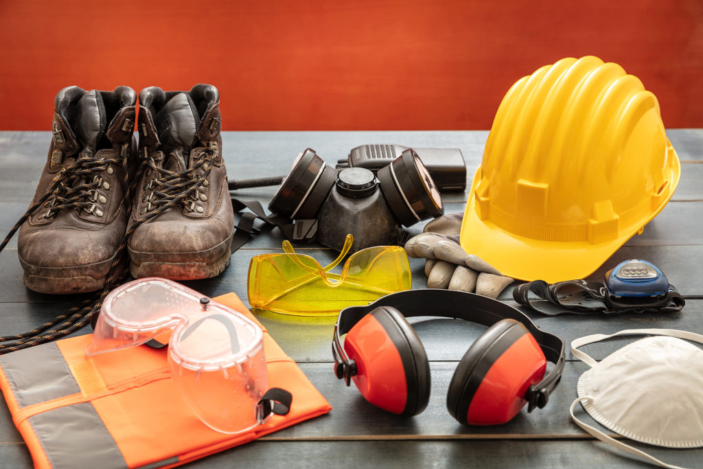 Work safety protection equipment flat lay. Industrial protective gear on white background, closeup view. Construction site health and safety concept